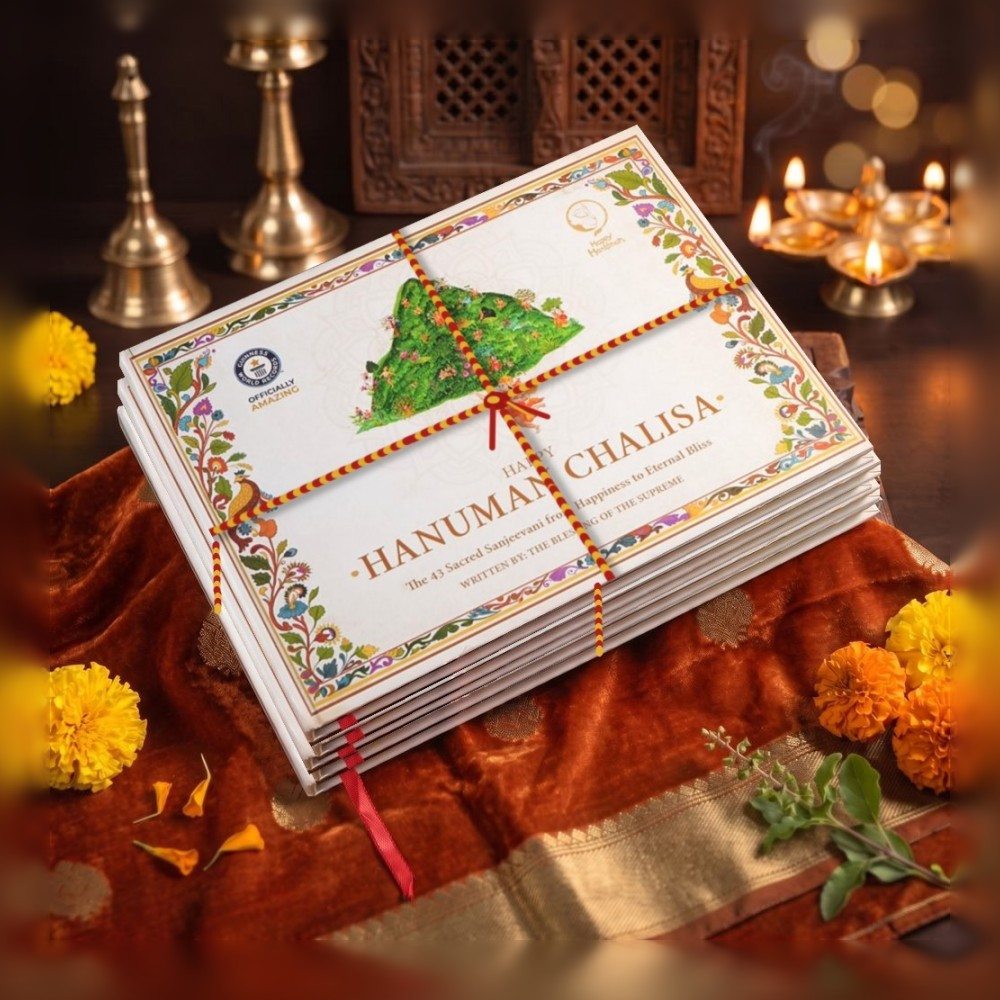 A stack of A4 Happy Hanuman Therapy Books tied with mauli thread on puja silk, with diyas and marigolds
